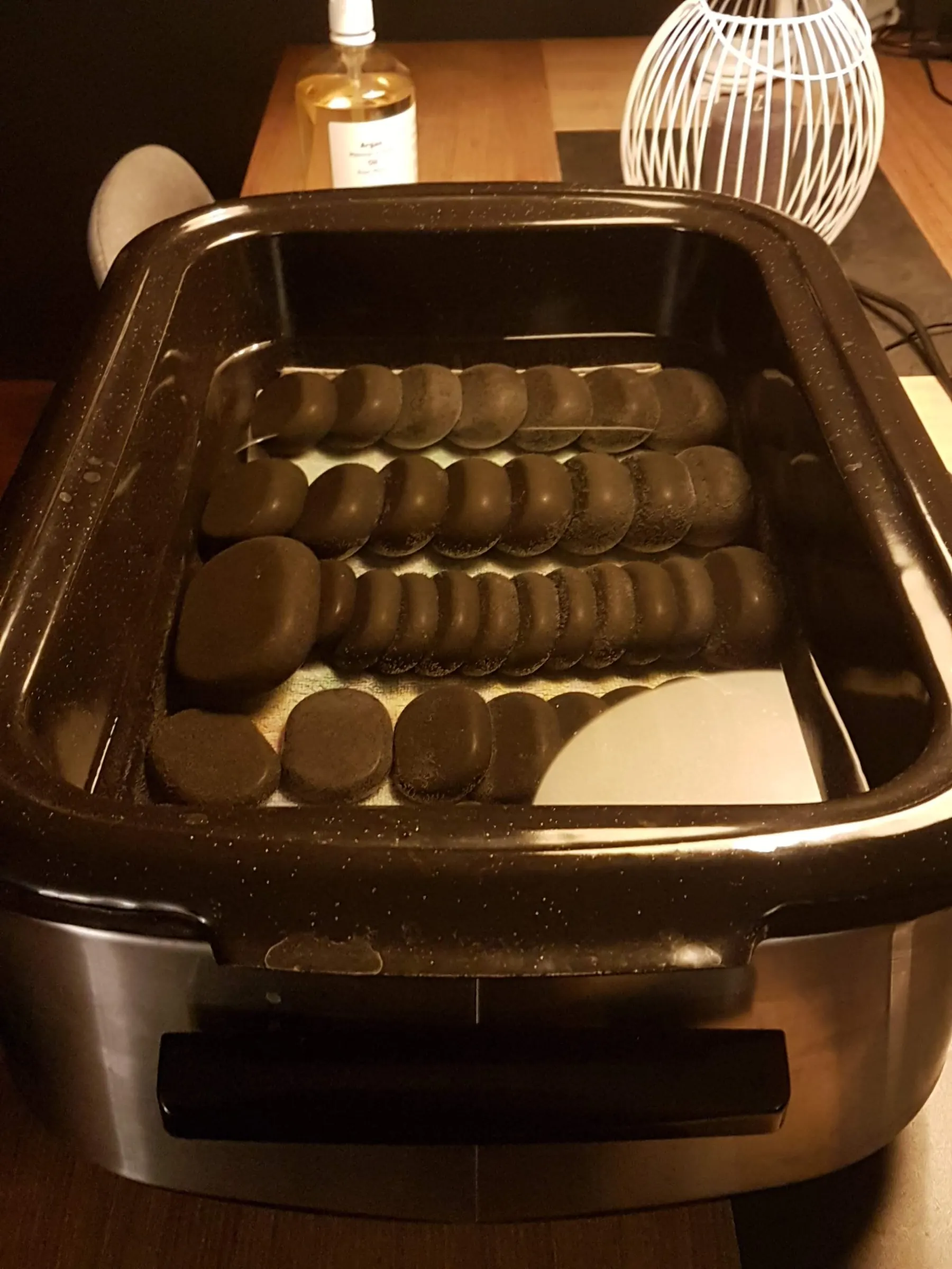 hotstones in een hotstoneheater met fles olie bij Massagepraktijk ALT